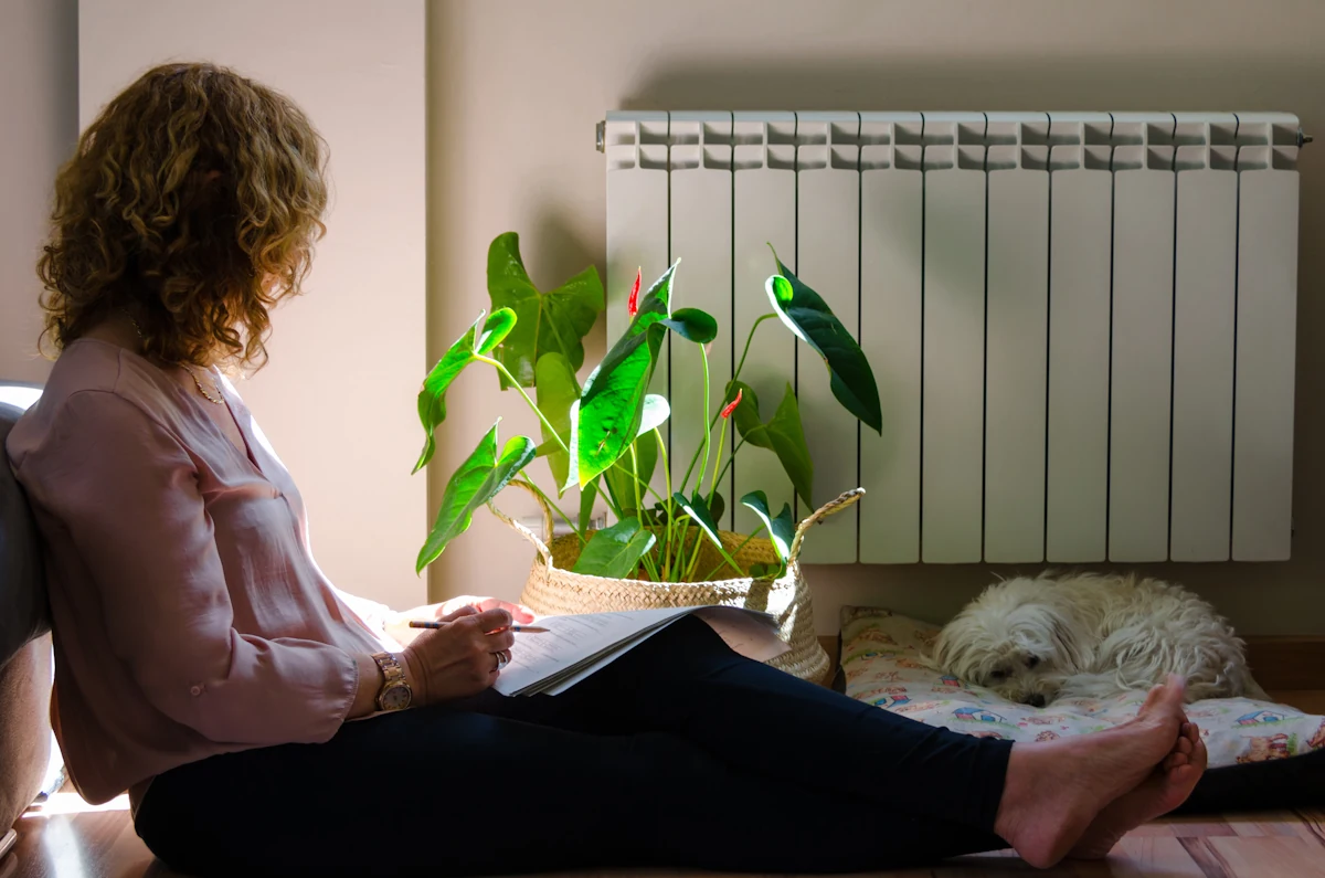 Une femme assise sur le sol près d'un radiateur