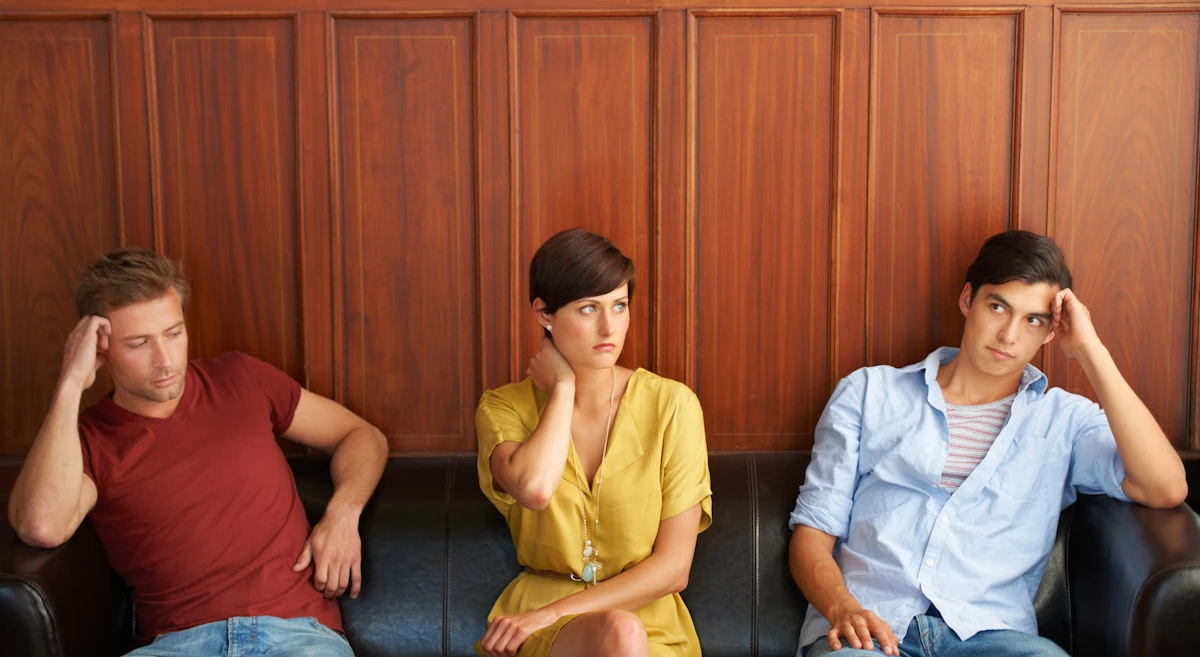 deux jeunes hommes et une femme assise au milieu qui ne se parlent pas