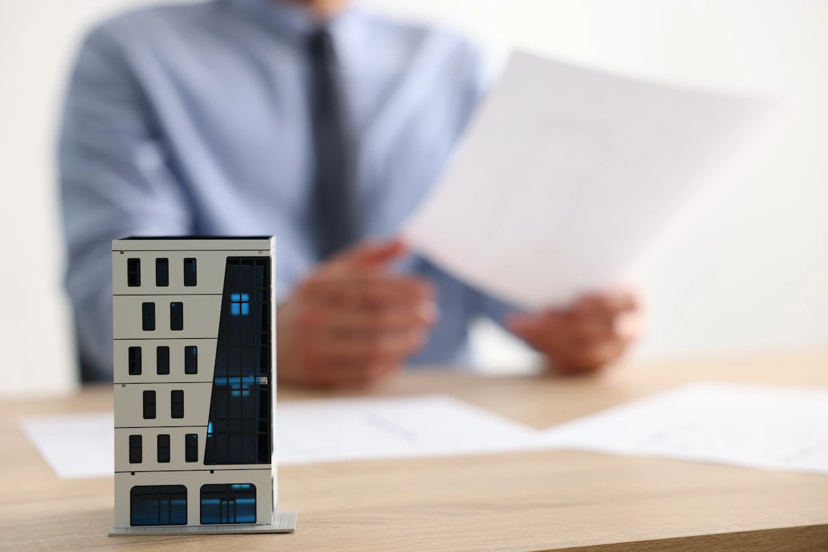 Un homme qui regarde un document devant une maquette de maison posée sur la table